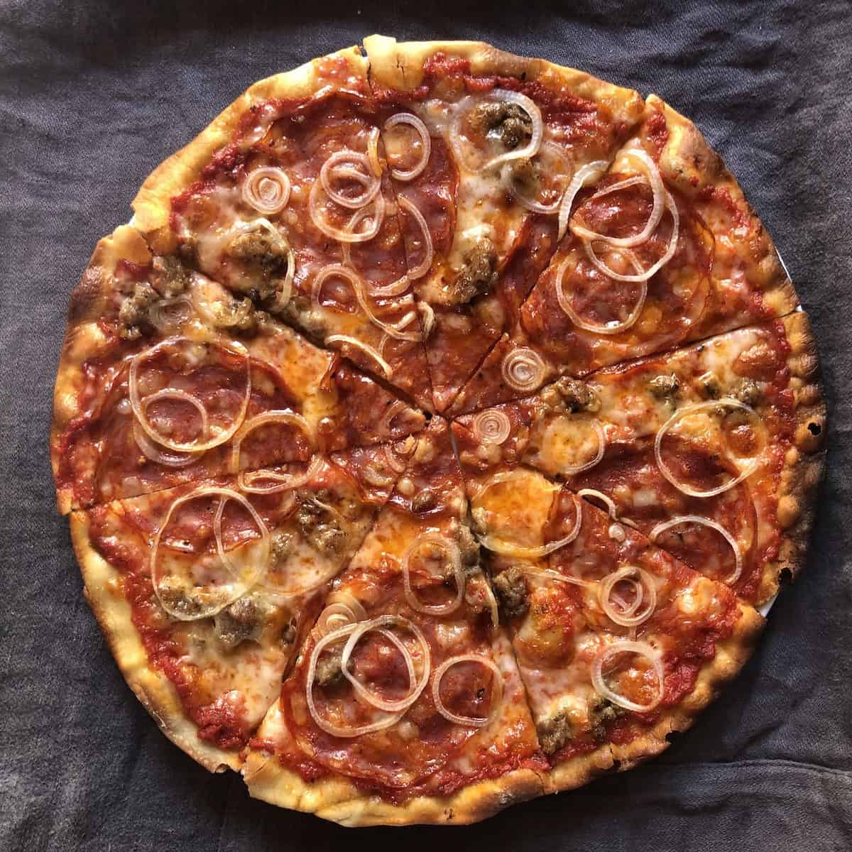 Golden brown sausage, pepperoni, 
and onion homemade pizza with a crispy pizza crust made with bread flour, how to make pizza crust from scratch using pizza dough with bread flour for the best pizza recipe.