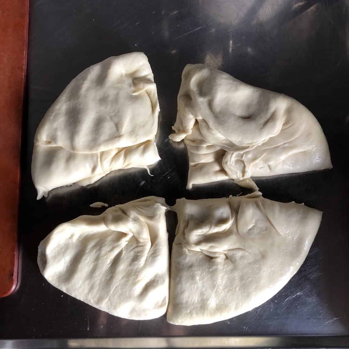 Portioned bread flour pizza dough on a floured surface ready to be formed into dough balls, homemade pizza dough recipe for the best pizza crust with bread flour.
