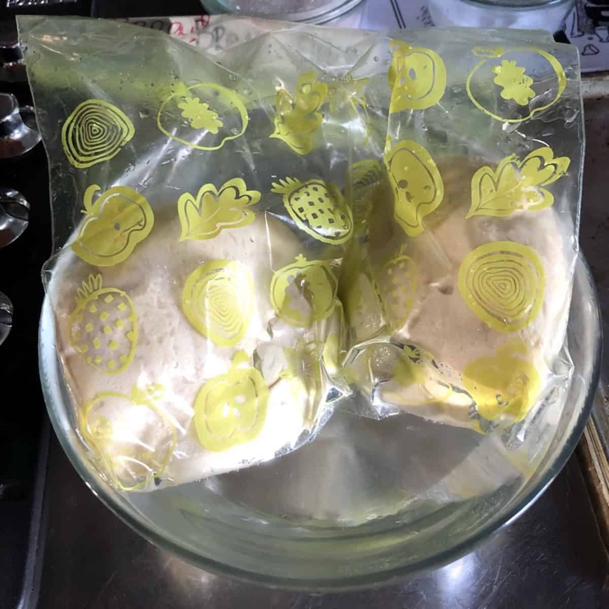 Frozen 00 flour thick crust pizza dough balls thawing in a bowl of warm water for a quick thaw or overnight in the fridge for thick-crust pizza dinners any night of the week.