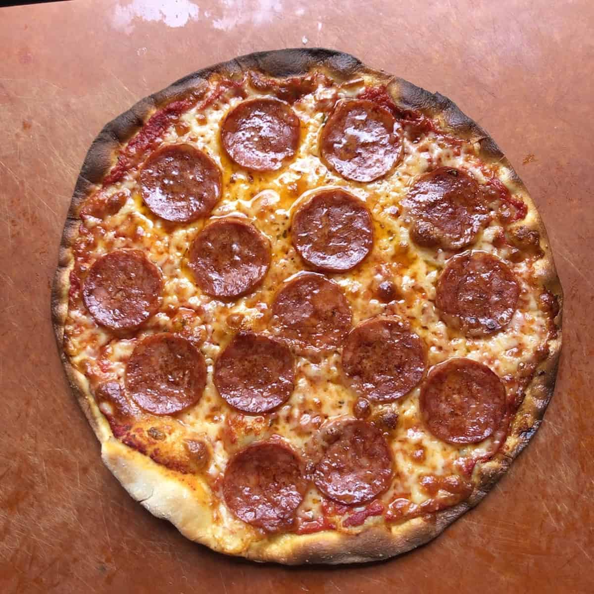 Pepperoni pizza with a bread flour pizza crust baked a few minutes too long with burnt edges, easy pizza recipe tip to keep an eye on your homemade pizza recipes as they cook.