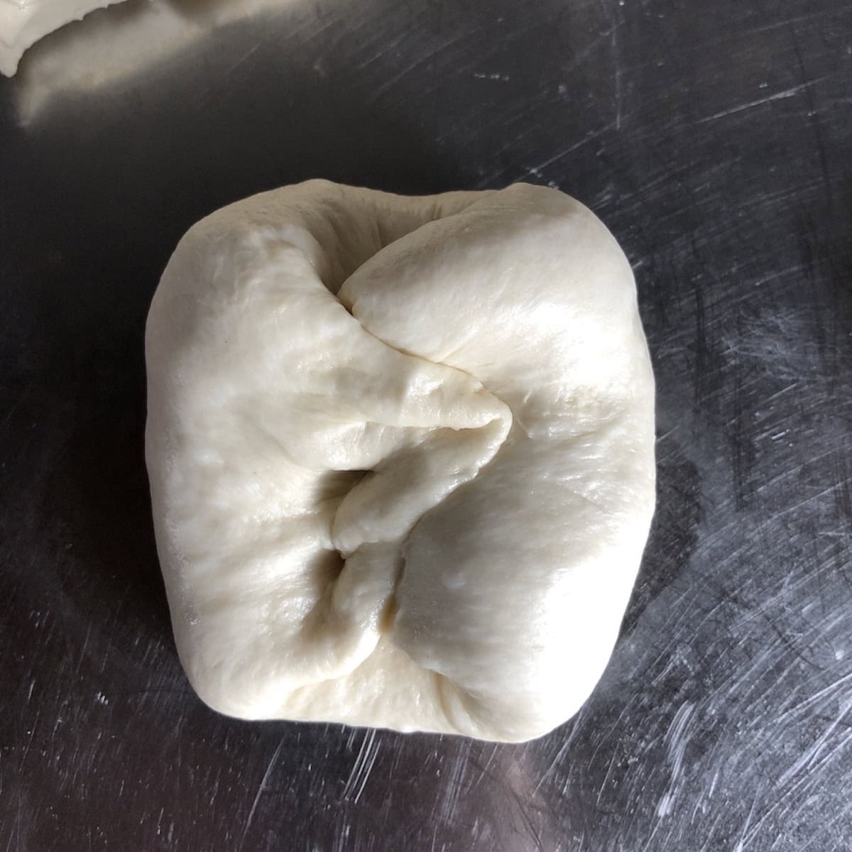 Folding king arthur bread flour pizza dough over itself like a business letter to form smooth dough balls, quick easy pizza dough technique for a basic pizza dough recipe from scratch.
