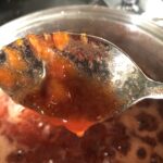 Showing the texture of a properly jelled jam as it drops from a spoon.