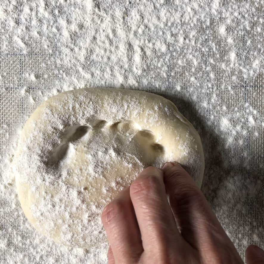 My fingers creating a pizza crust perimeter that before hand tossing the pizza and stretching it out to be sauced and topped.