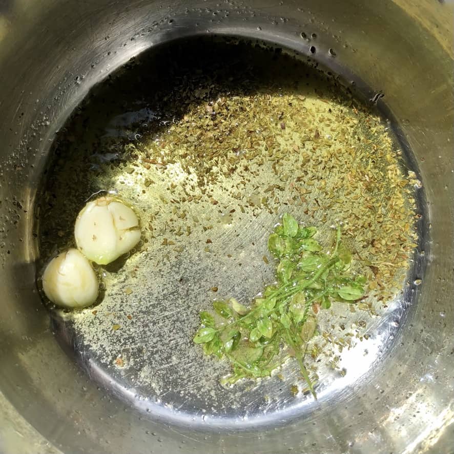 Blooming the herbs and garlic in a medium sized pot with extra virgin olive oil, 2 smashed garlic cloves, dried and fresh oregano.