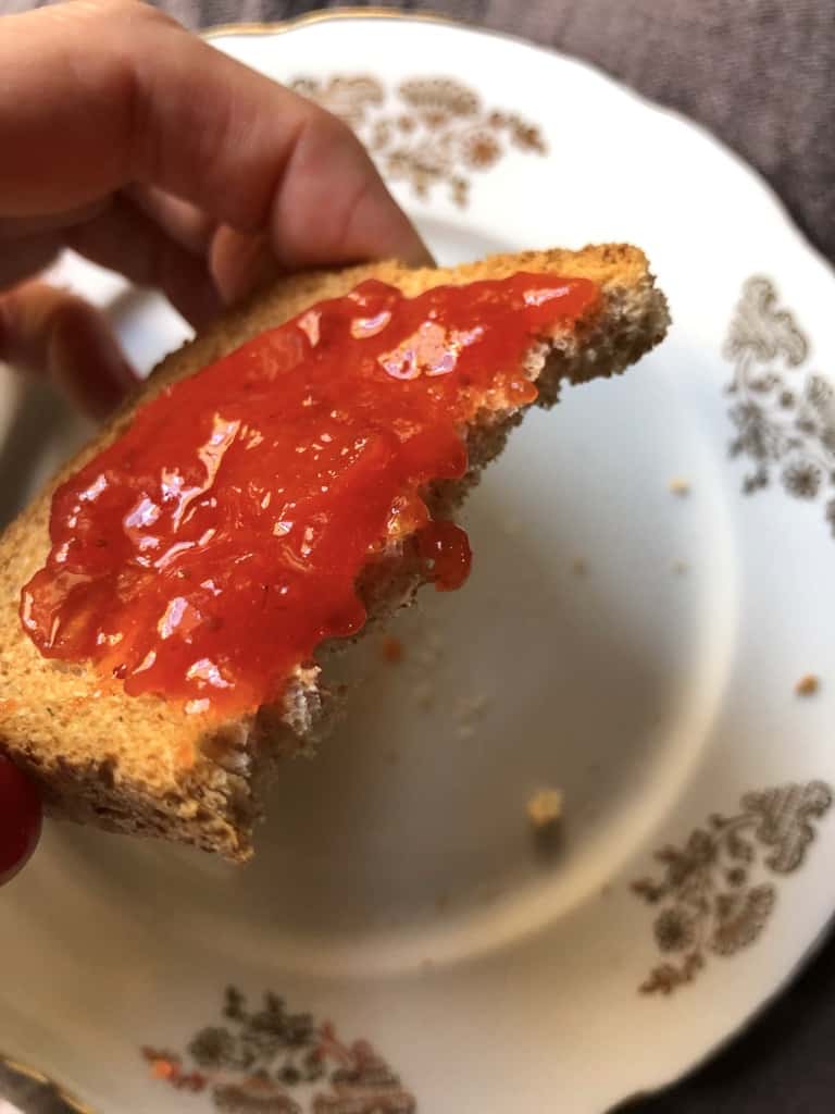 A half eaten piece of Italian toast smeared with homemade jam.