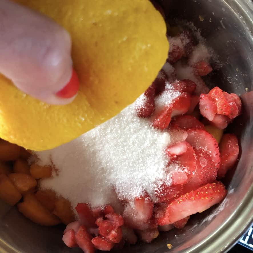Squeezing fresh lemon juice into the fruit jam mixture.