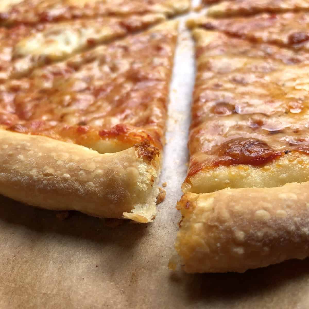 Sliced homemade pizza made with 00 flour thick crust pizza dough topped with san marzano DOP tomatoes, melted mozzarella, grana padano, and buffalo mozzarella.