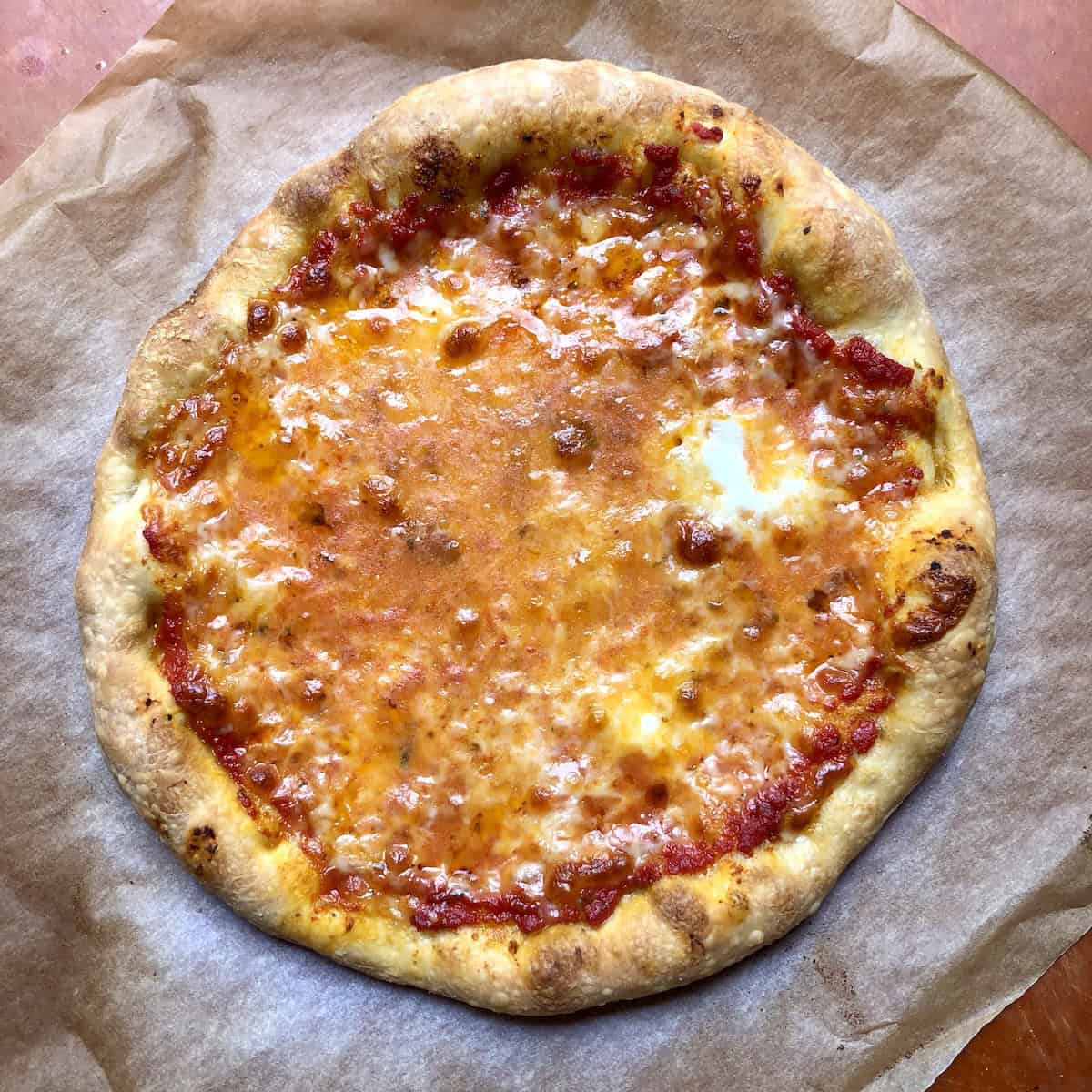 
Best homemade pizza with thick crust pizza dough showing ooey gooey melted mozzarella and golden brown crust fresh from the oven.
