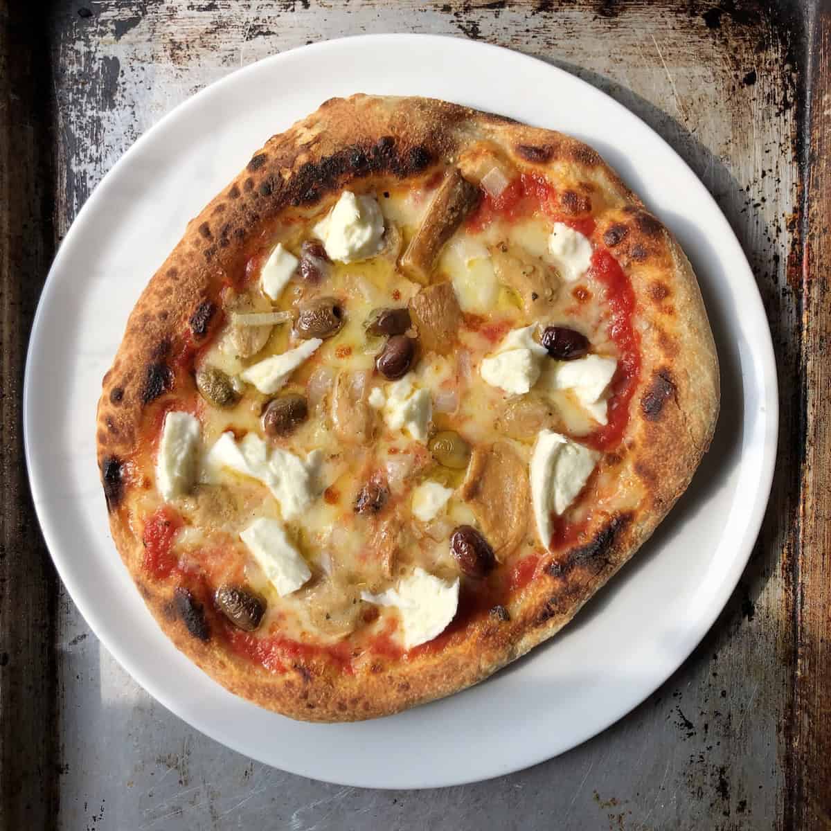 Thick crust pizza recipe with porcini mushrooms, taggiasca olives, and onions baked golden brown and blistered in an electric pizza oven, chewy pizza dough recipe for the best thick crust pizza.