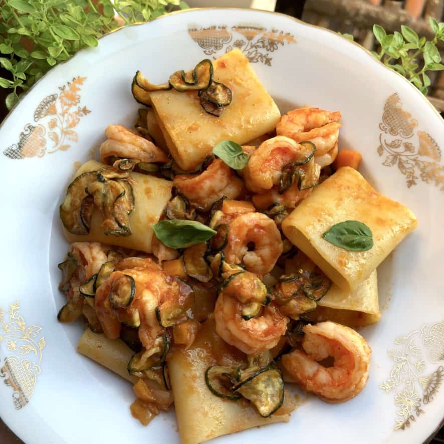 A beautiful bowl of seafood paccheri pasta with shrimp and zucchini in a tomato and white wine sauce.