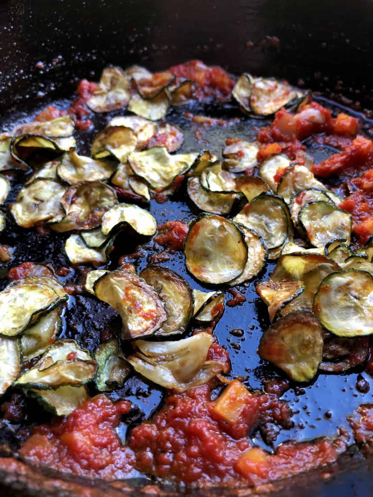Lightly fried zucchini and tomatoes in a skillet to make the paccheri pasta sauce.