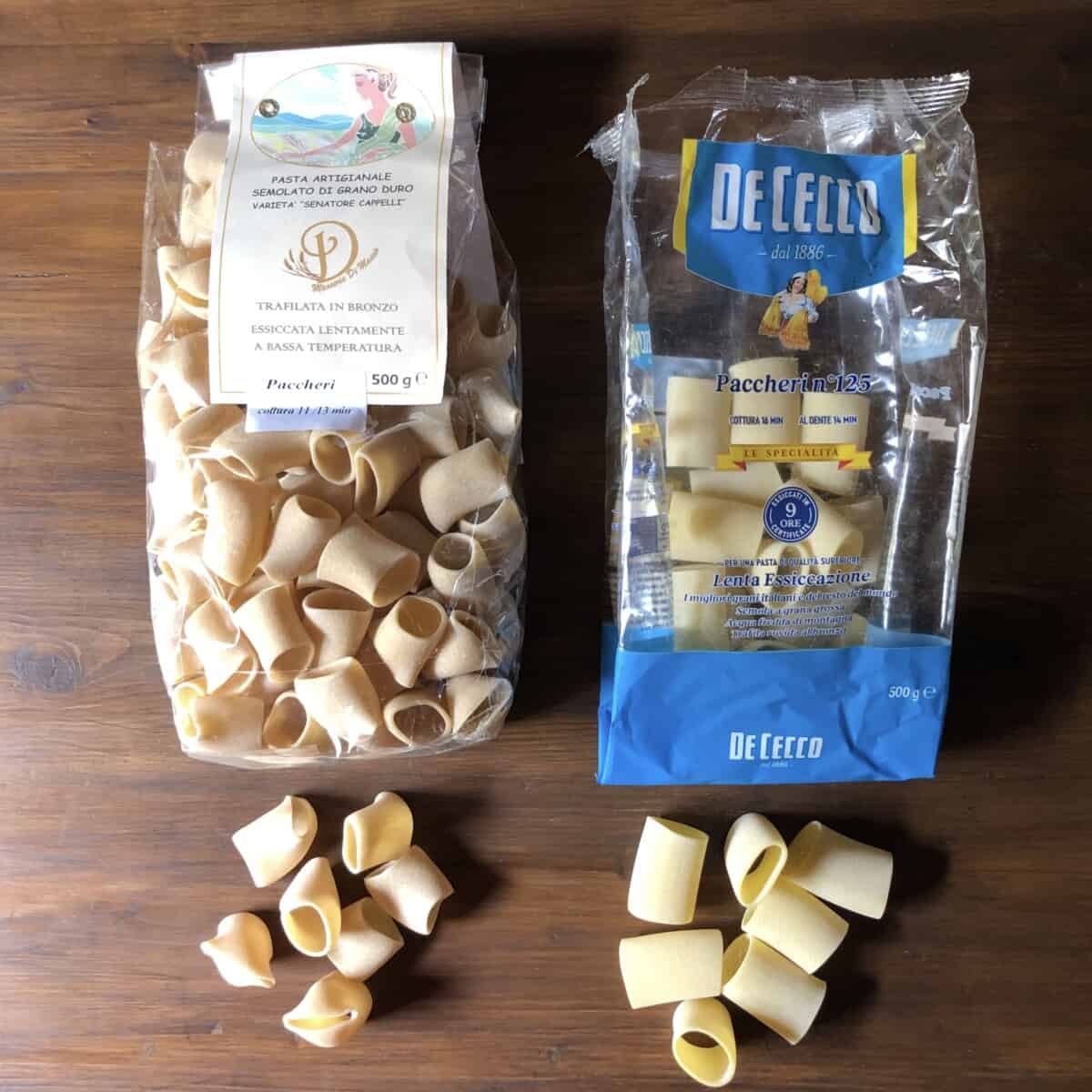 Two bags of Italian paccheri dried pasta: on the left, an artisanal paccheri pasta bronze drawn and made in Abruzzo, Italy and on the right, De Cecco pasta paccheri no. 125 paccheri pasta.