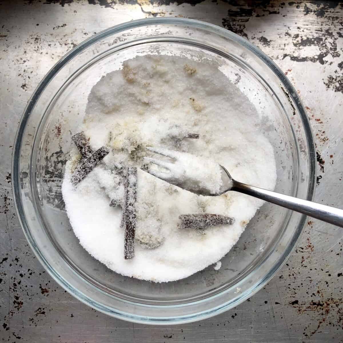 stirring vanilla bean seeds and cut vanilla beans into the sugar using a dessert fork.