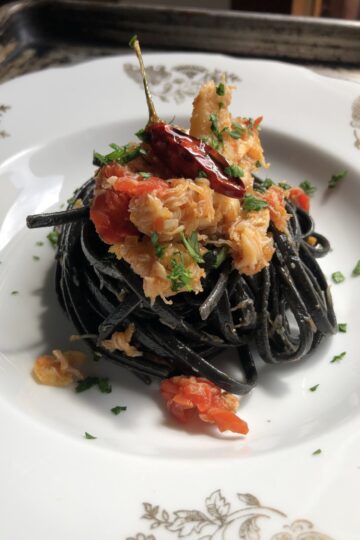 Squid Ink Linguine with Crab pasta in a pasta bowl with crab and tomatoes wine sauce.