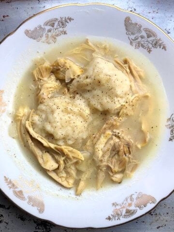 Closeup of a bowl of chicken and dumplings with fluffy drop dumplings in a rich broth ready to eat.
