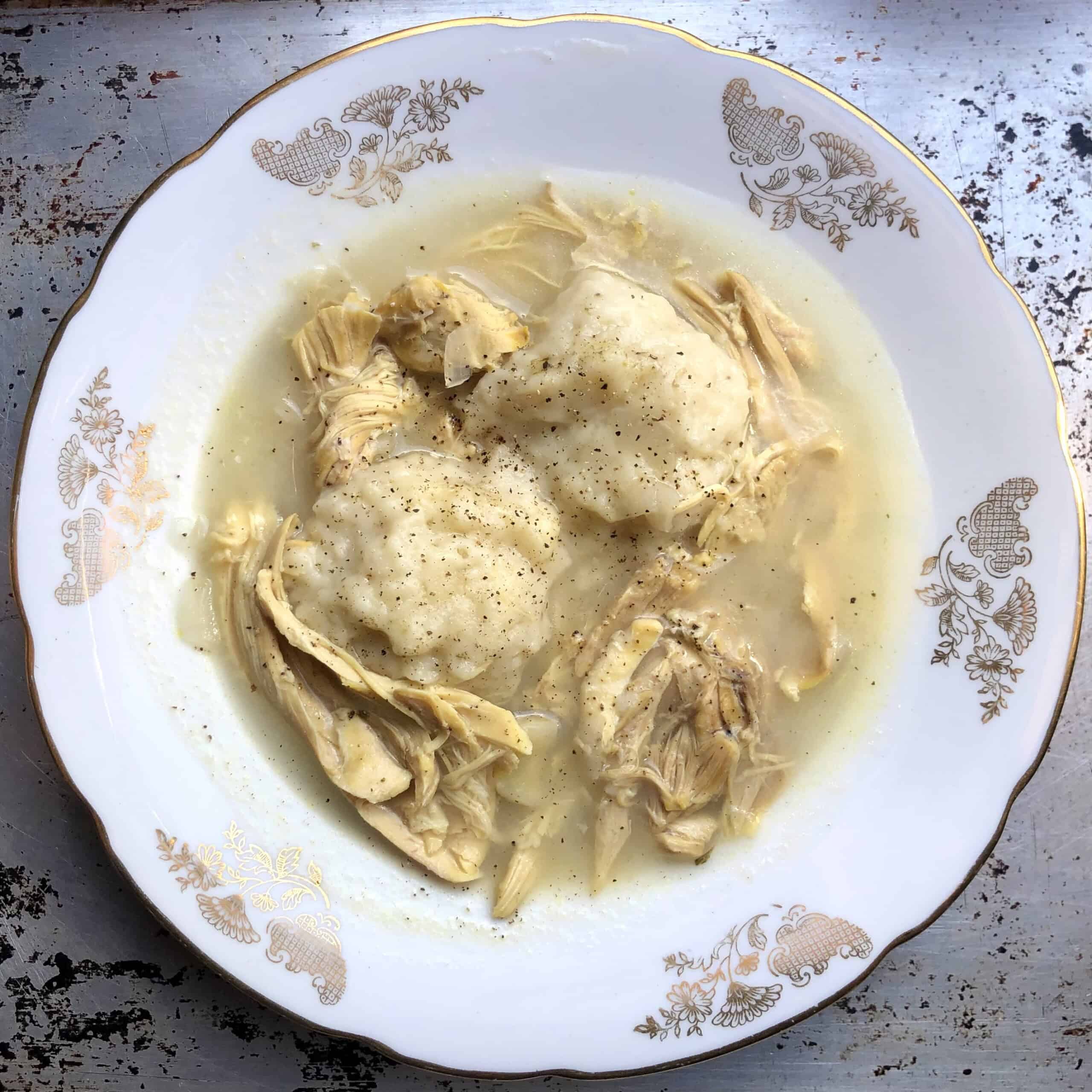 Closeup of a bowl of chicken and dumplings with fluffy drop dumplings in a rich broth ready to eat.