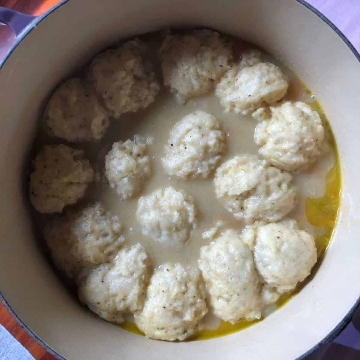 Perfectly steamed fluffy dumplings in the pot of old fashioned chicken and dumplings ready to portion and serve.