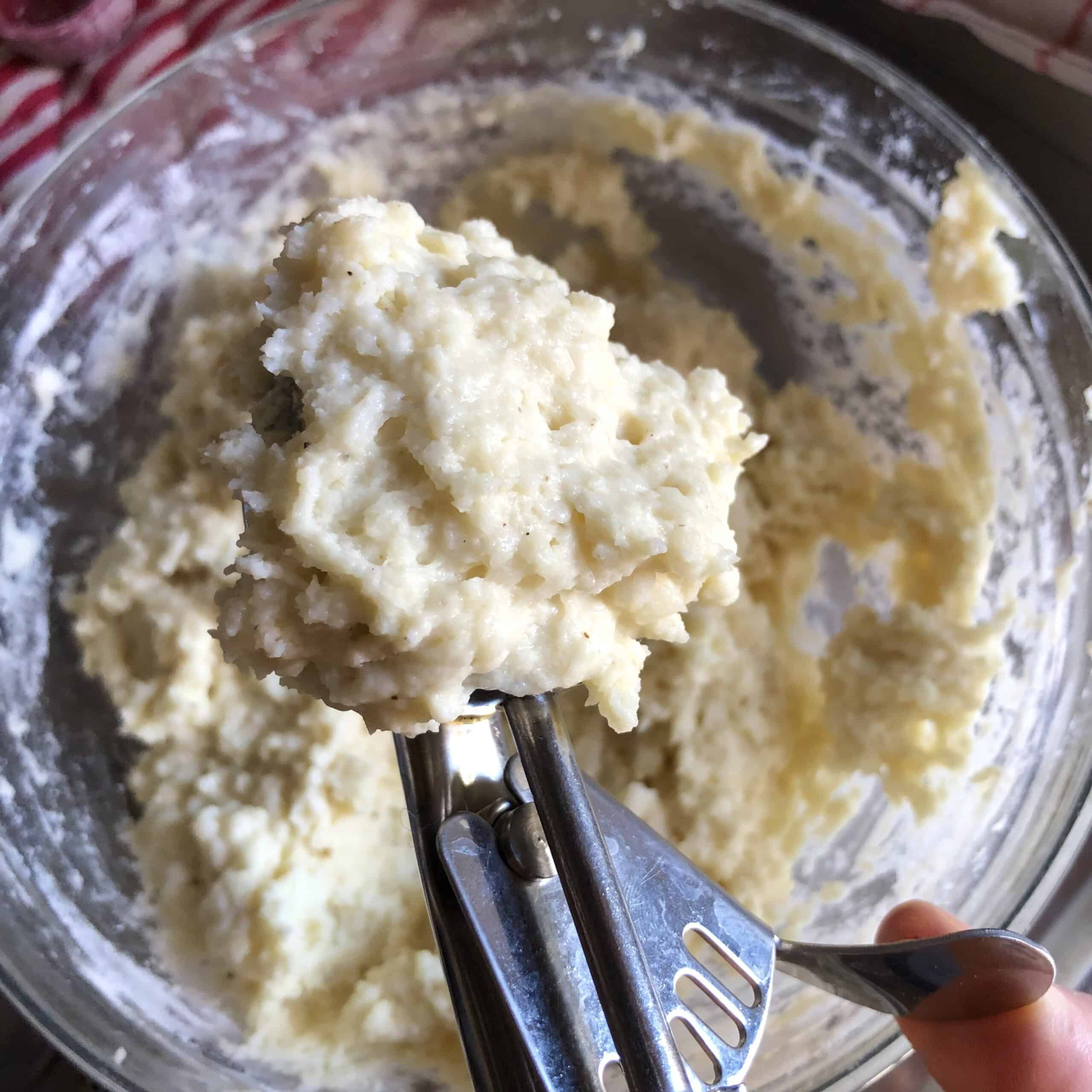 A scoop of drop dumpling batter in a portioning scoop ready to add to the pot, old fashioned chicken and dumplings recipe.