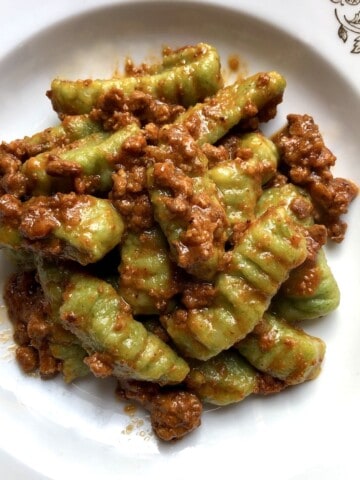 A bowl of spinach gnocchi bolognese ready to serve, gnocchi recipe with homemade bolognese sauce on potato spinach gnocchi.
