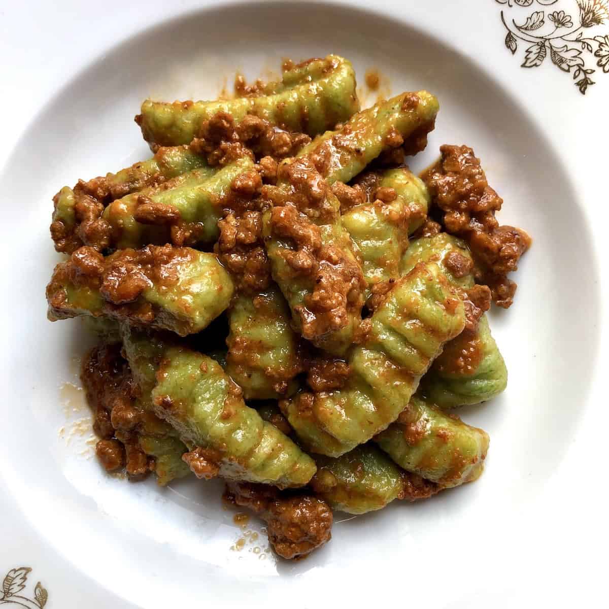 A bowl of spinach gnocchi bolognese ready to serve, gnocchi recipe with homemade bolognese sauce on potato spinach gnocchi.