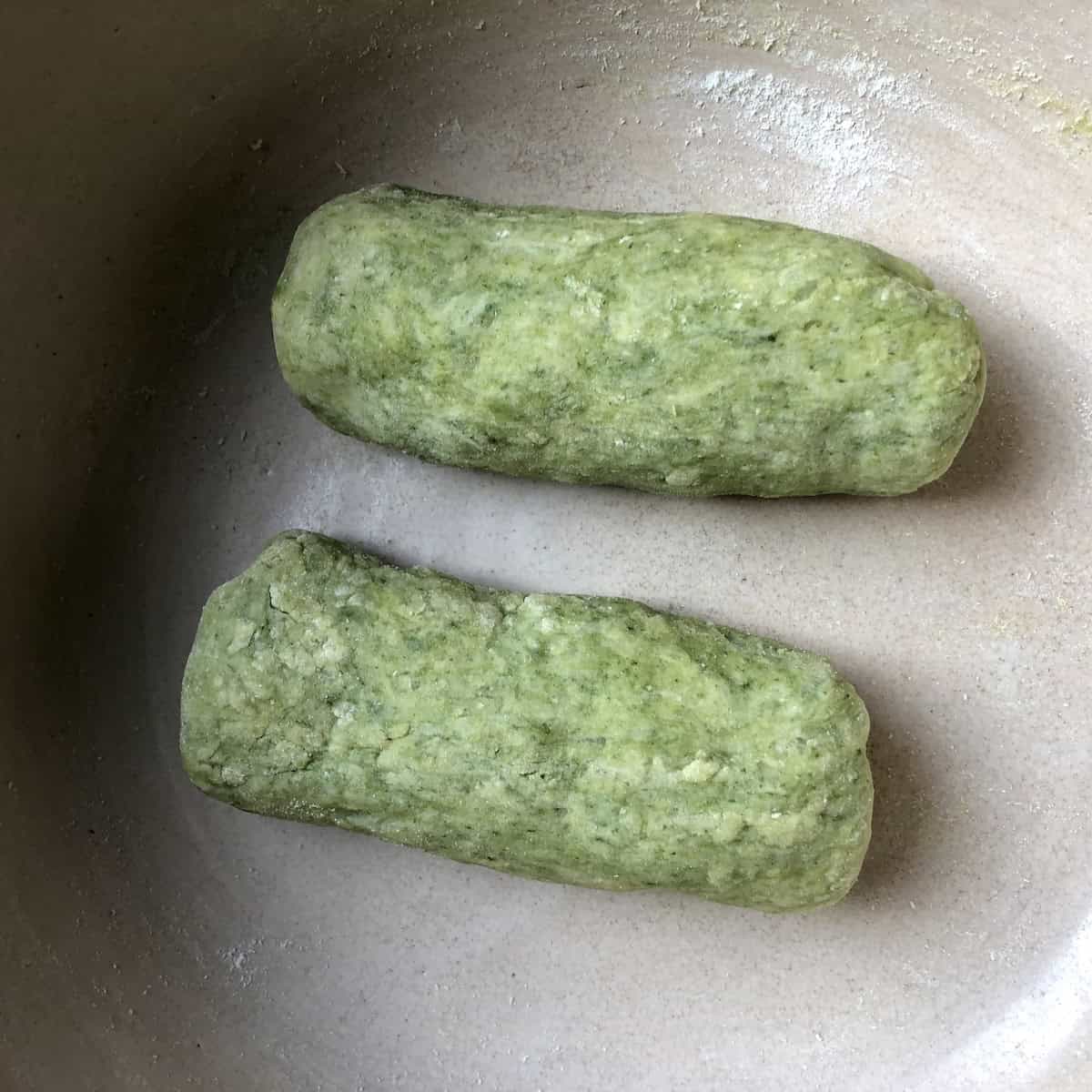 Spinach gnocchi dough log cut into two smaller logs ready to roll, spinach gnocchi recipe step by step.
