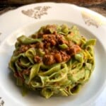 A pasta bowl filled with luxurious ribbons of green tagliatelle with bolognese sauce all made from scratch (Tagilatelle con ragù made the Bologna way).
