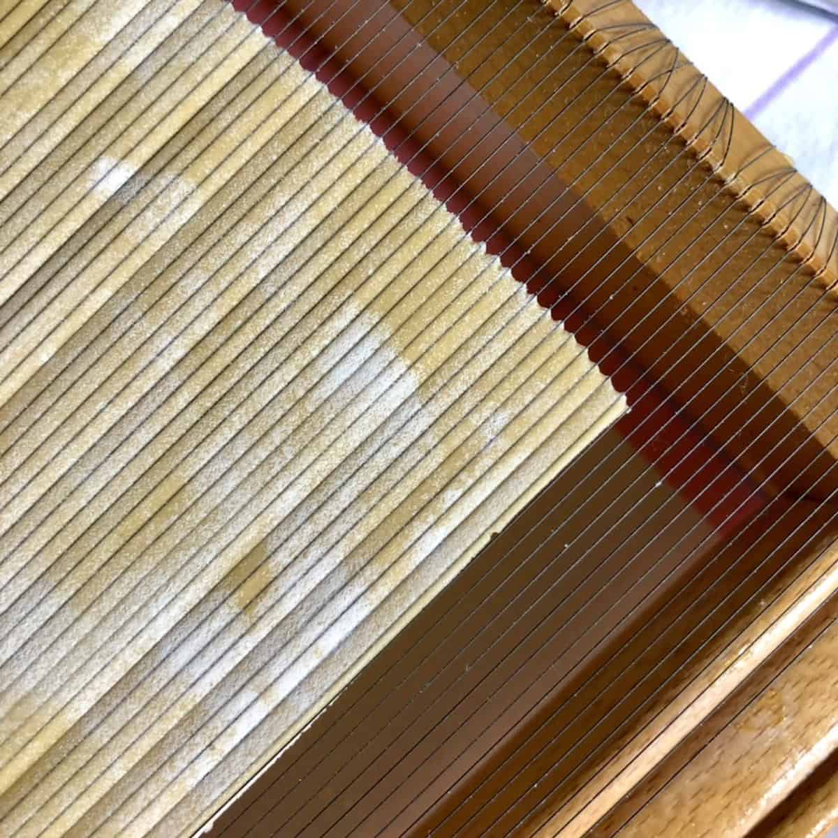 Closeup of pasta dough rolled over a chitarra with square spaghetti not yet released from the wires, chitara guitar pasta cutting step.
