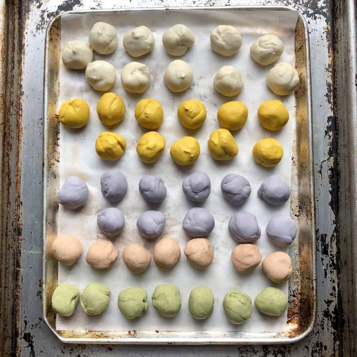 Pink, purple, yellow, white, and green naturally colored dumpling wrapper dough balls ready to roll out and fill for chinese dumplings.