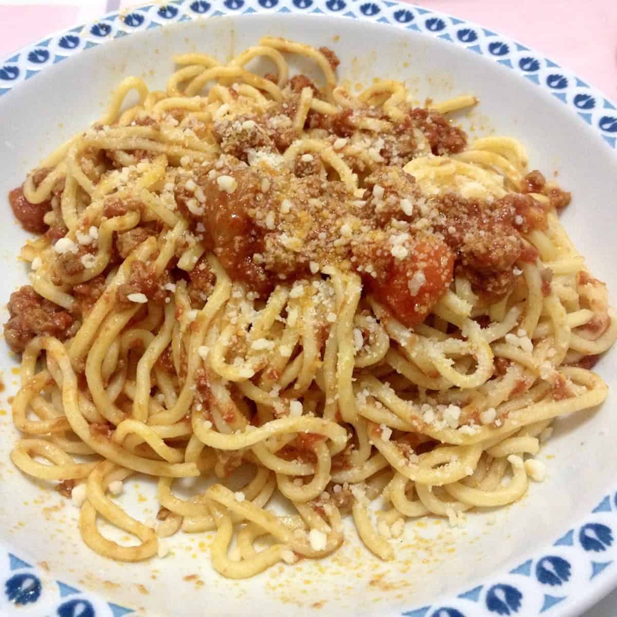 A bowl of spaghetti alla chitarra with sugo di salsiccia e pomodori (sausage tomato sauce) pasta alla chitarra from Abruzzo ready to eat.
