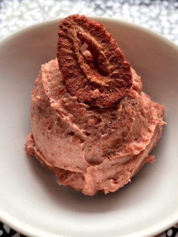 Strawberry butter scooped into a white bowl (looks like dark pink ice cream) with a freeze dried strawberry slice garnish.