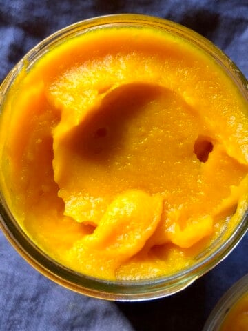 Homemade pumpkin puree in glass mason jar for pumpkin pancakes, pumpkin bread, pumpkin waffles, pumpkin pasta, pumpkin, etc. (image showing fresh pumpkin puree for making pumpkin pancakes from scratch instead of canned pumpkin).