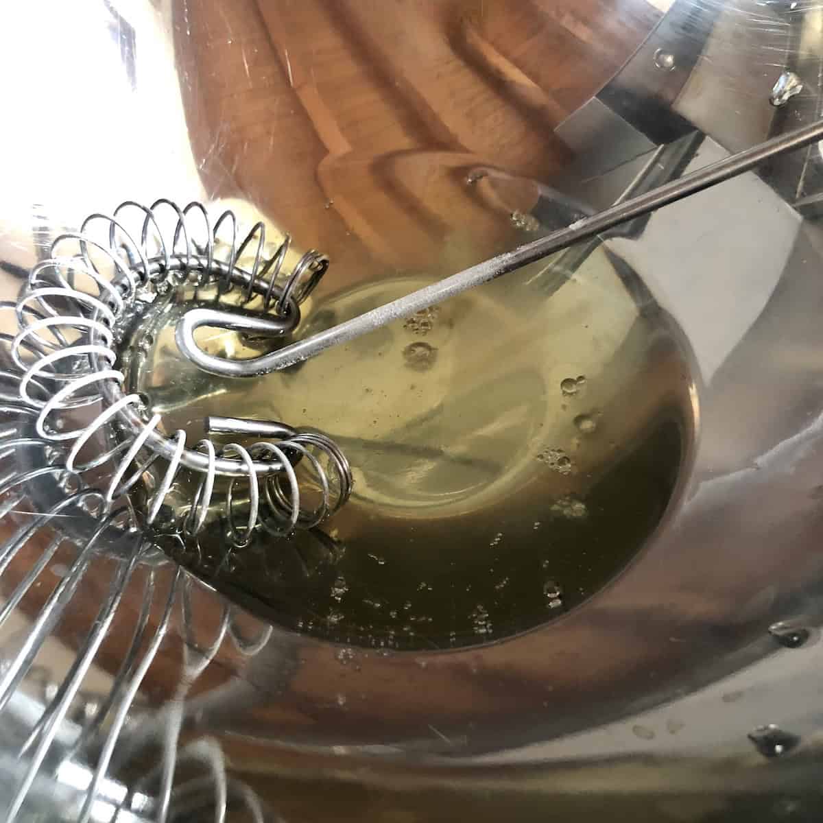 Separated egg whites in bowl for fluffy pumpkin pancakes recipe showing wet ingredients preparation for light and fluffy pumpkin pancakes from scratch.
