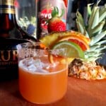 Aurum Orange Liqueur cocktail with rum and freshly juiced fruit punch rimmed with homemade orange sugar.