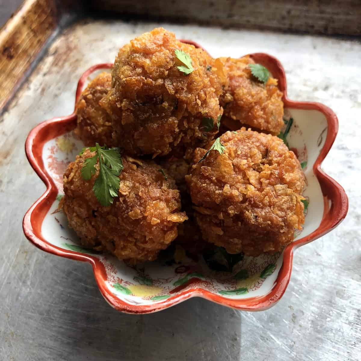 Homemade authentic fried Teochew shrimp balls served in a Chinese hand painted porcelain dish garnished with fresh cilantro leaves, showcasing the classic presentation and how crispy they are!