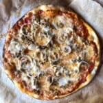 Delicious thin and crispy crust pizza topped with homemade sausage pizza topping and onions, showcasing the perfect combination of savory meat and caramelized onions not yet cut.