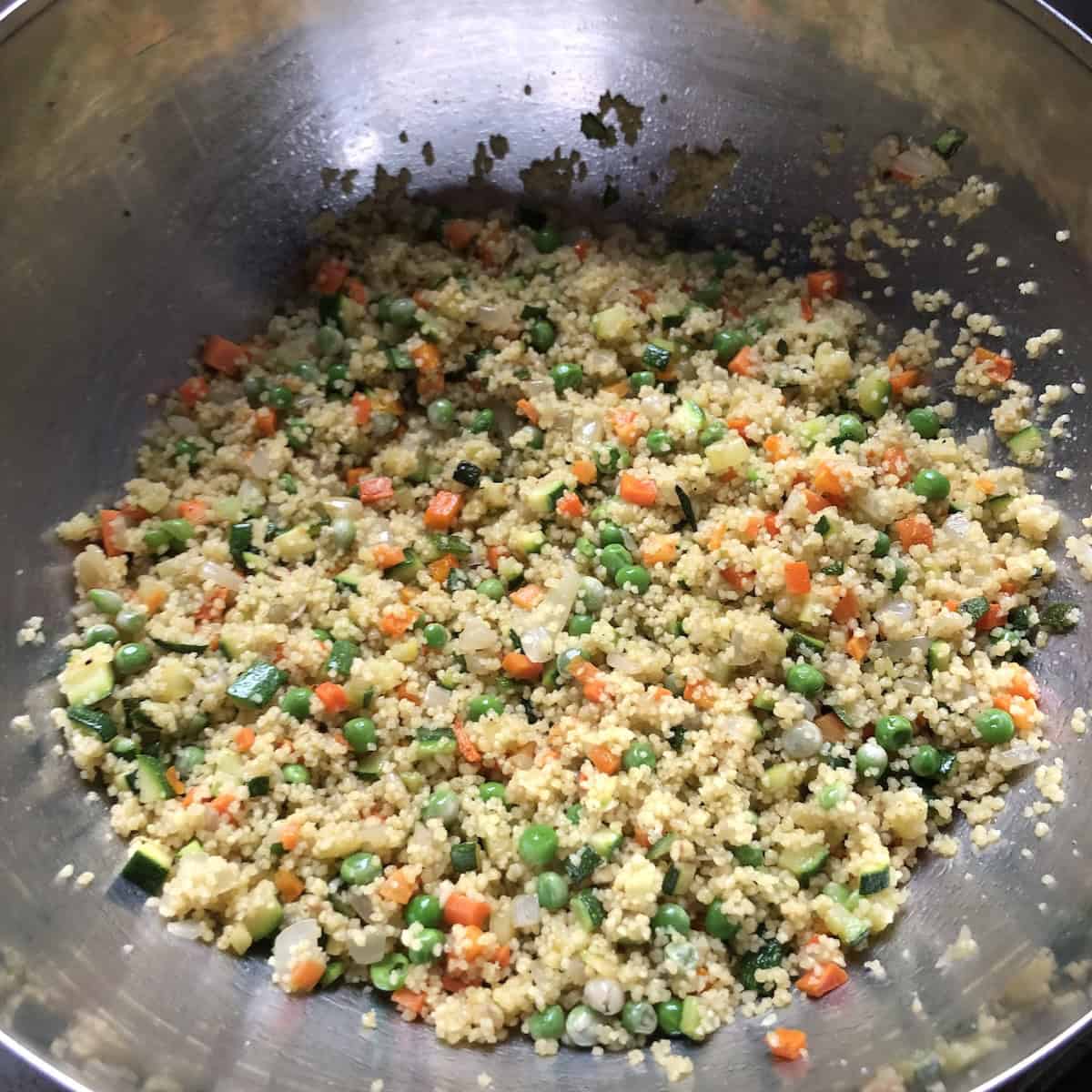 Authentic Italian Mediterranean vegetable couscous recipe showing perfectly cooked couscous mixed with caramelized carrots, zucchini and peas, creating a complete homemade dish that's healthier and more flavorful than store-bought versions, perfect for meal prep or as a versatile side dish.
