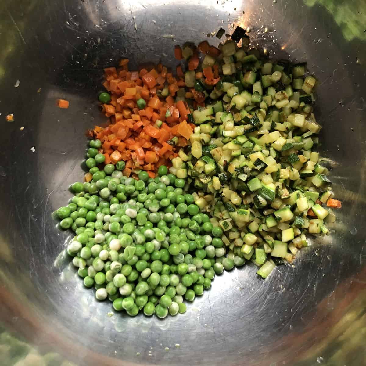 Sauteed carrots, zucchini, and peas in a mixing bowl for authentic Italian Mediterranean vegetable couscous, showcasing the unique technique of caramelizing each vegetable separately to build depth of flavor in homemade couscous recipes.