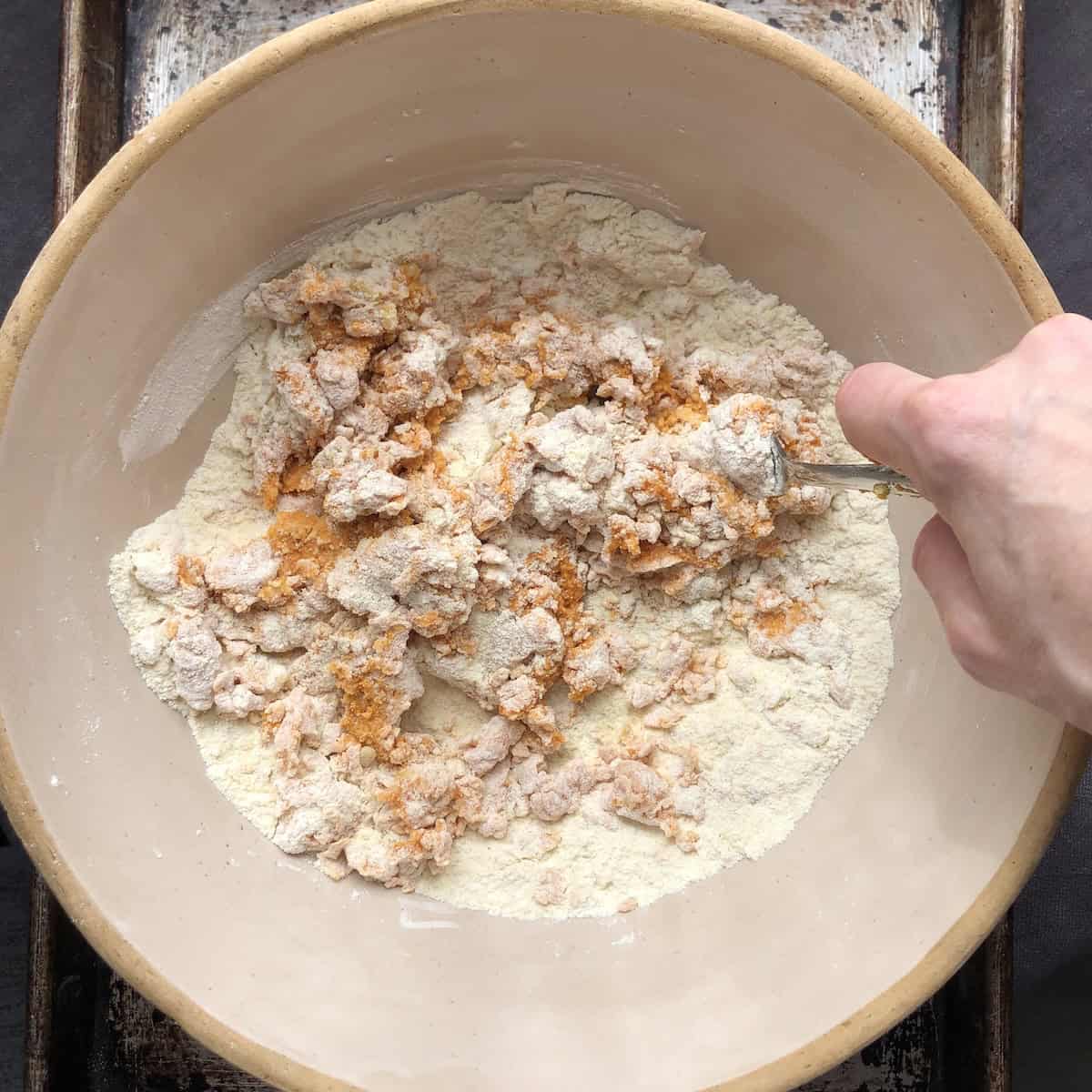 Mixing in the pumpkin puree mixture and EVOO into flour mixture with fork for homemade pumpkin pasta dough.
