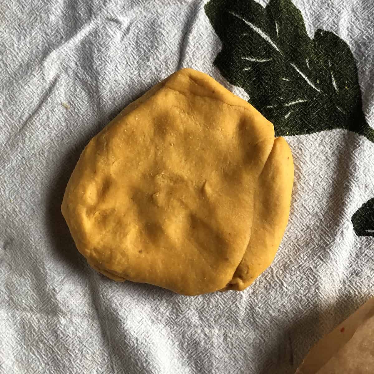 Flattened pumpkin pasta dough ready for pasta machine widest setting to make homemade pumpkin pasta.
