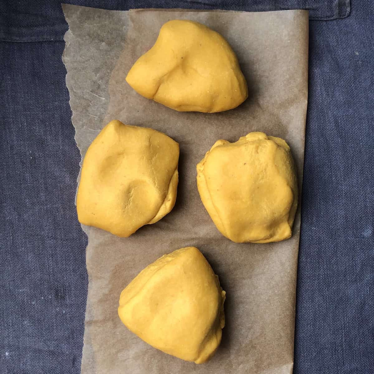 Four portioned pumpkin pasta dough pieces.
