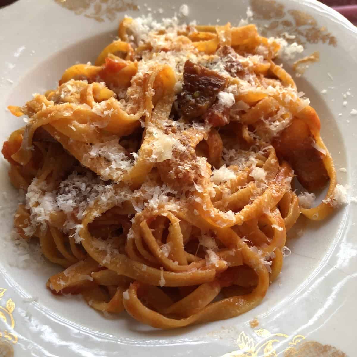 Pumpkin pasta recipe all'amatriciana with guanciale and pecorino Romano with orange homemade pumpkin pasta noodles in a pasta bowl.
