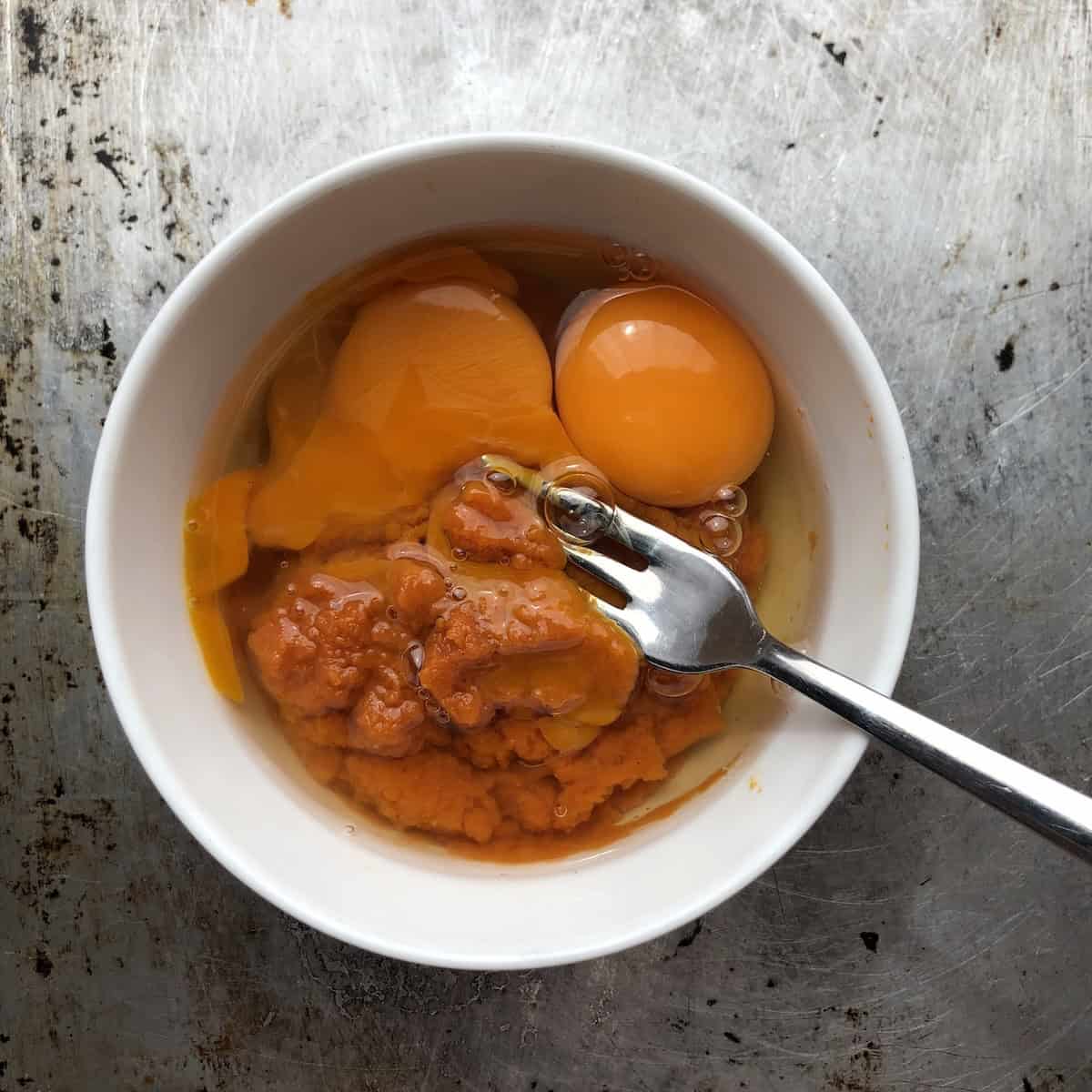 Pumpkin pasta recipe showing eggs and canned pumpkin puree in a bowl before whisking to combine.
