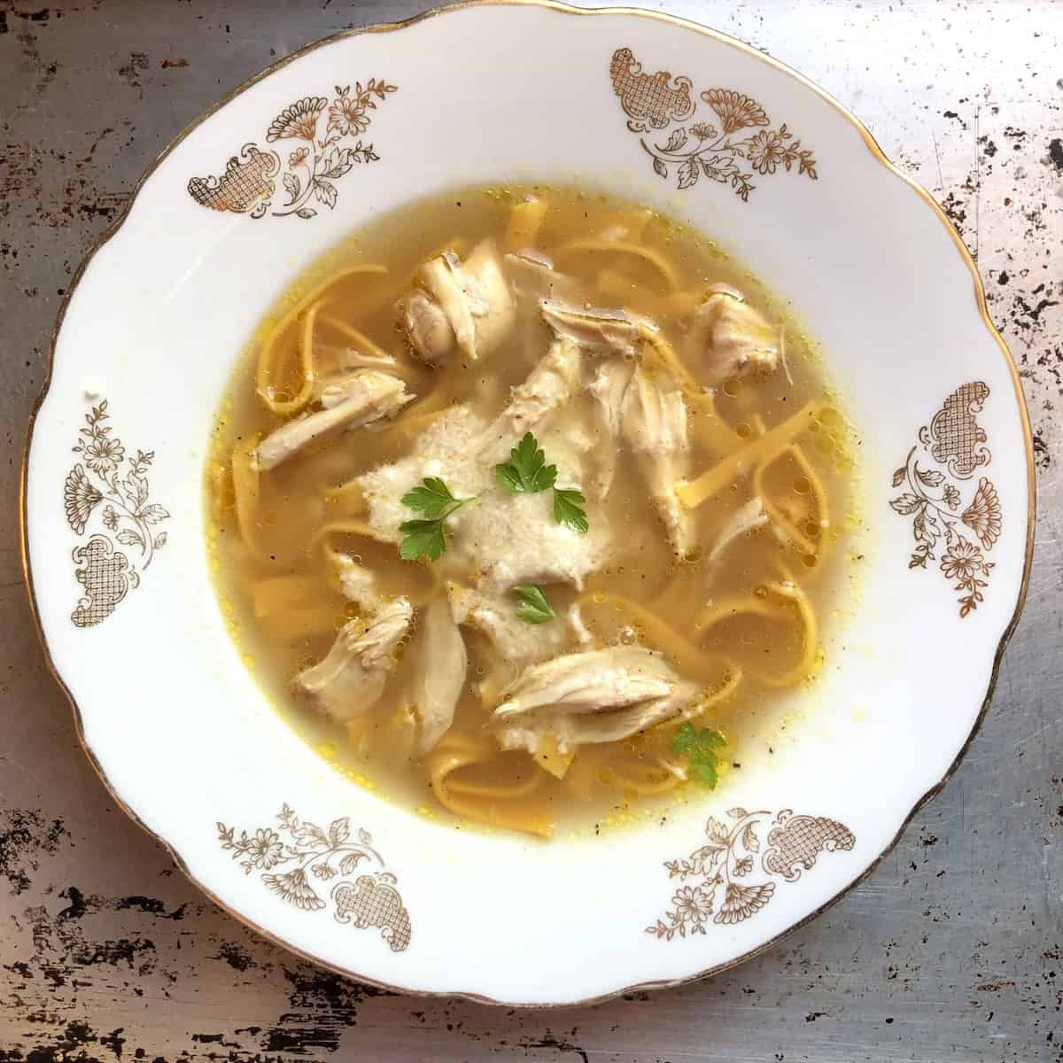 Pumpkin pasta noodles in homemade chicken noodle soup, pasta with pumpkin dough recipe showing fresh orange pumpkin noodles in broth with chicken and vegetables for easy pumpkin recipes and fall comfort food dishes.