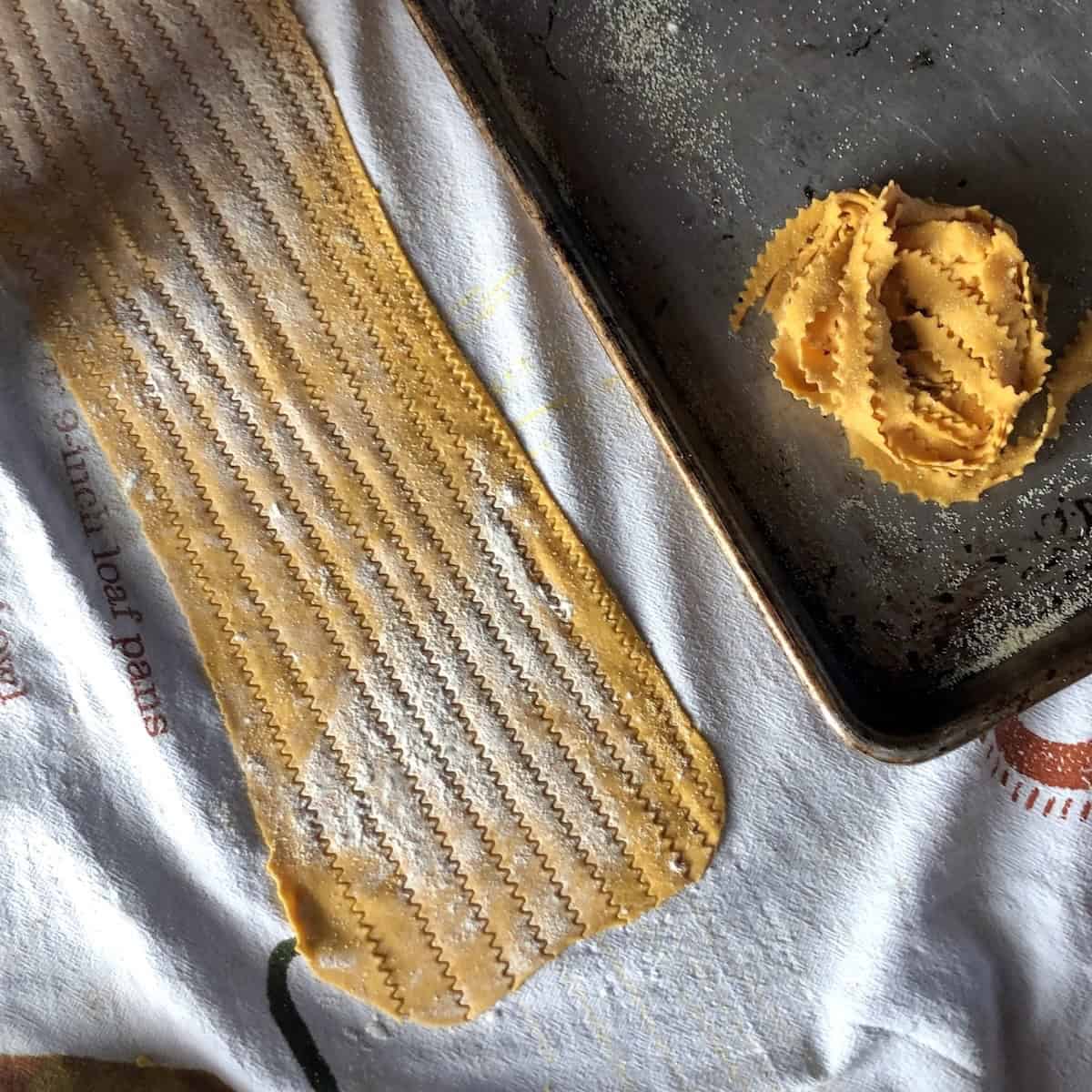 Cutting pumpkin pasta reginelle fettuccine and reginelle pappardelle with zigzag pasta wheel for homemade pumpkin noodles.