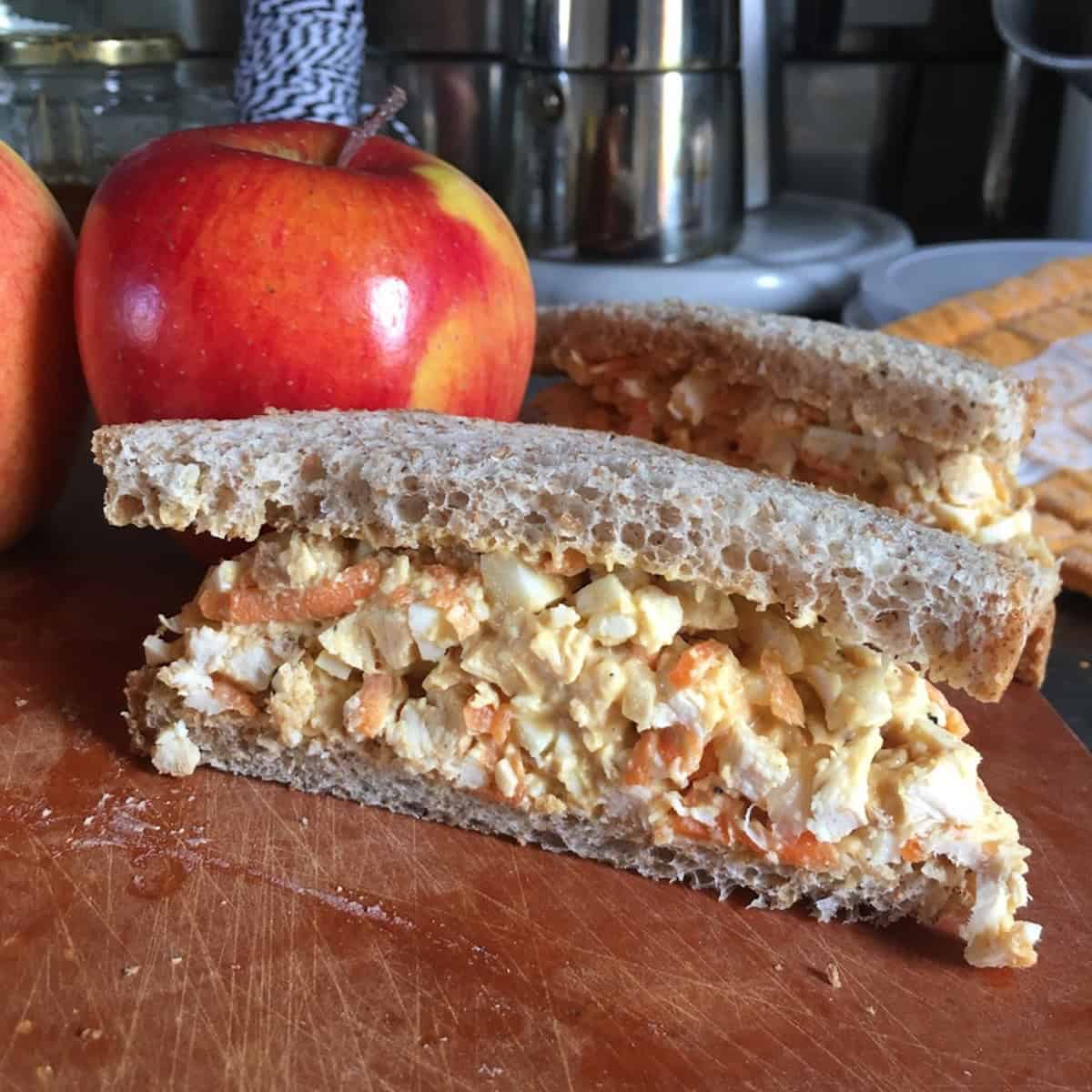 Homemade chicken salad sandwich on wheat bread cut in half using spent chicken leftover from making homemade chicken broth recipe for zero waste cooking.
