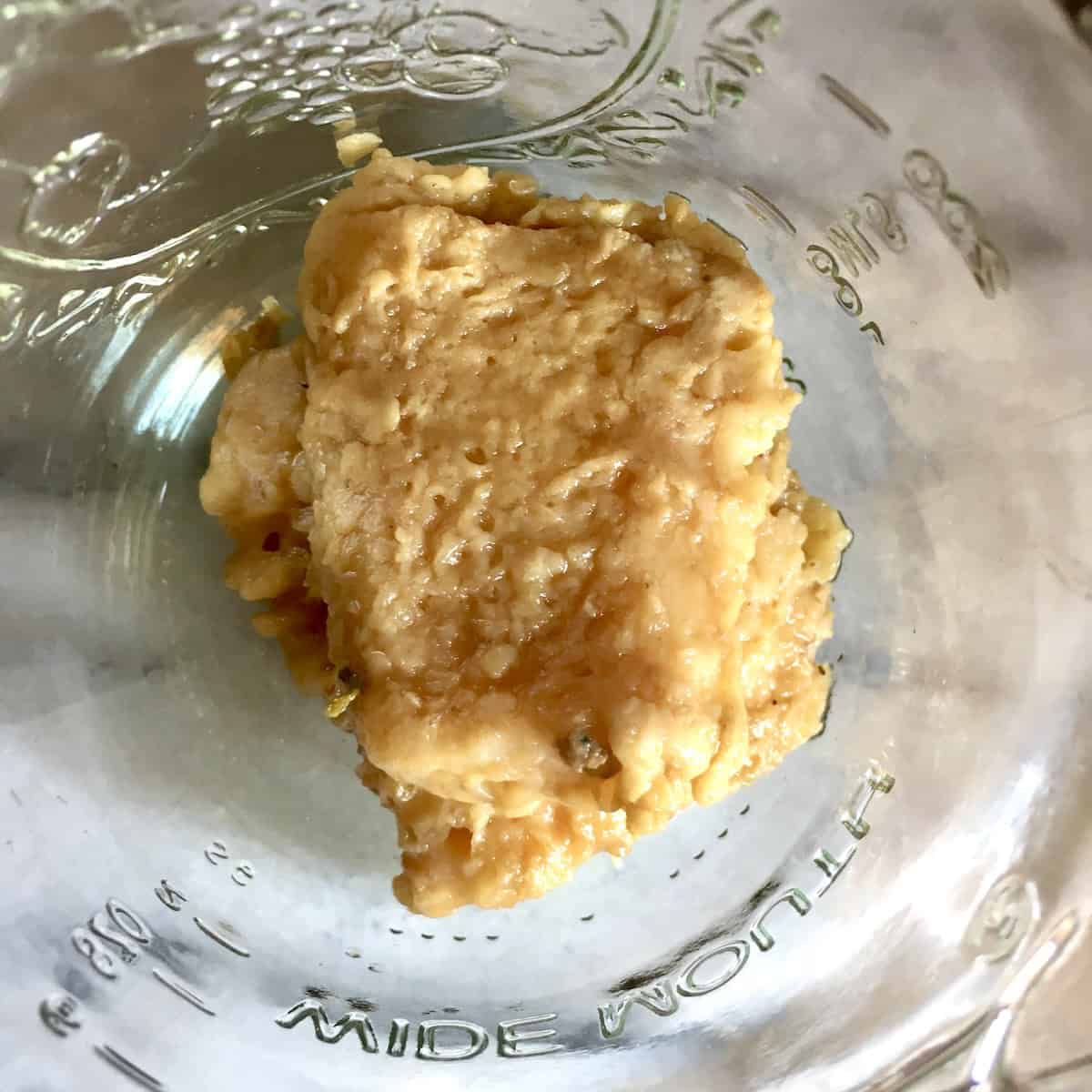 Cooked grana padano cheese rind after flavoring homemade chicken broth recipe showing edible leftover ingredient that can be eaten or discarded.
