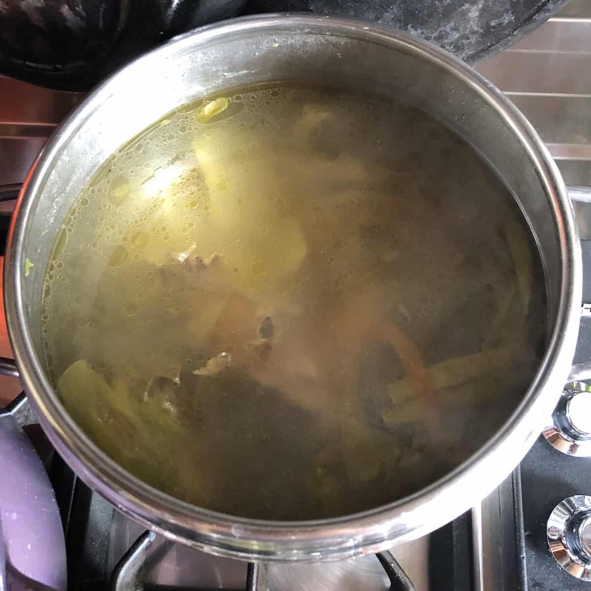 Opened pressure cooker showing fully cooked chicken broth finished and ready to strain for homemade chicken broth recipe pressure cooker method.
