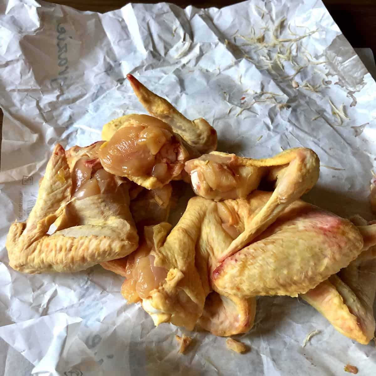 Pile of organic raw chicken wings for making homemade chicken broth recipe with collagen rich wing bones for best chicken bone broth.