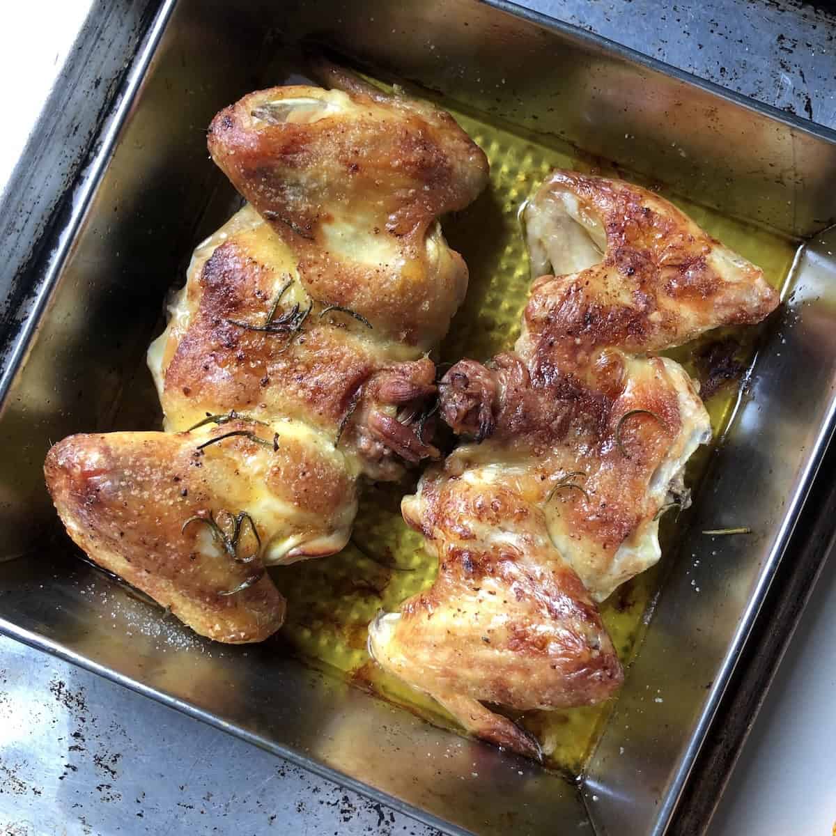 Two roasted crispy golden chicken backs with wings and necks attached for making best homemade chicken stock with collagen rich bones.