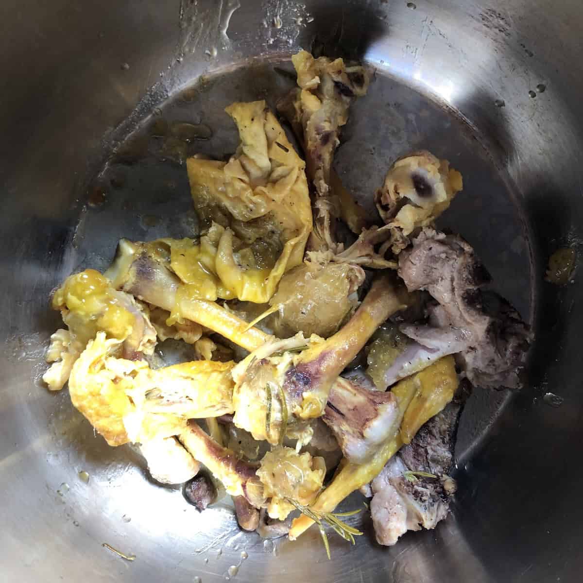 Roasted chicken bones in pot ready to make rich flavorful homemade chicken broth recipe for best bone broth with deep color and flavor.